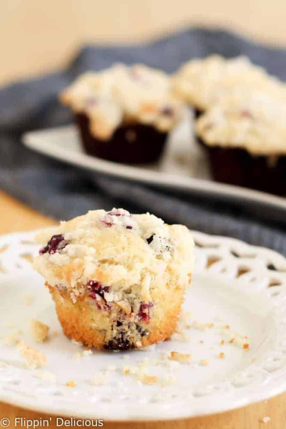 Gluten-Free Blueberry Muffin with Streusel Crumb Topping on a white plate.