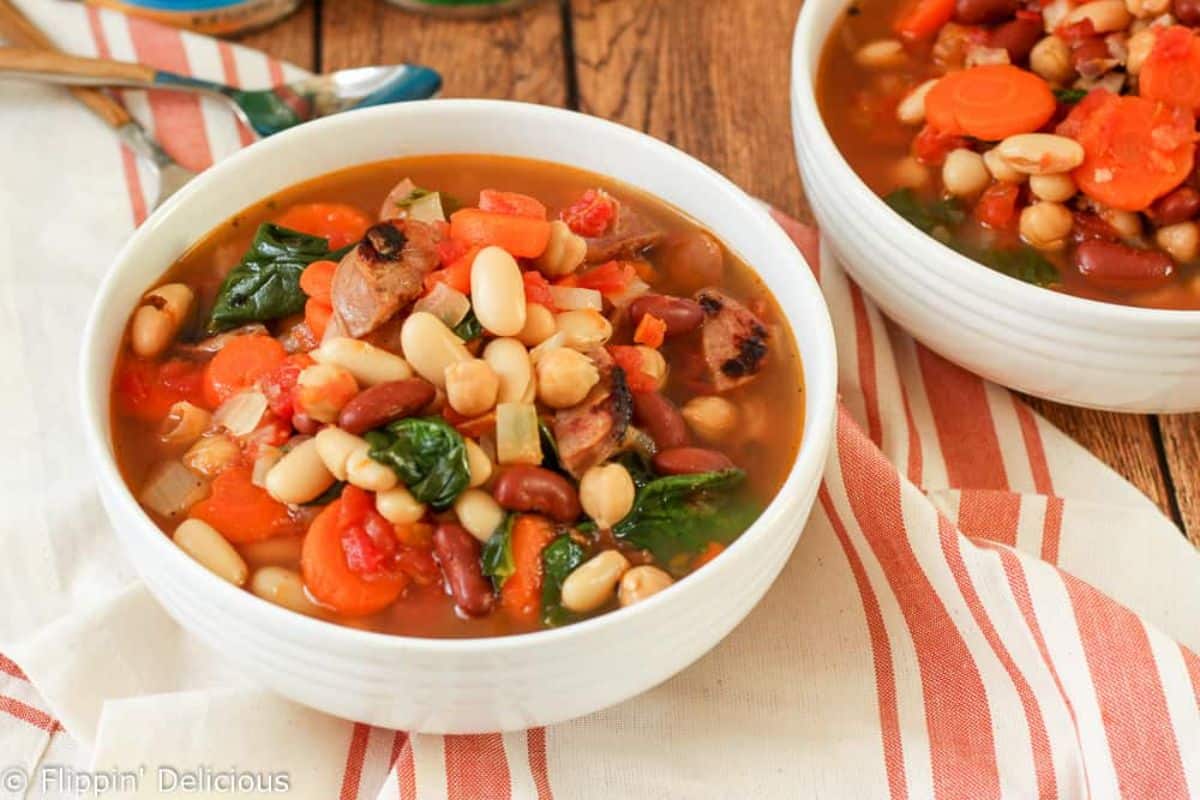 Delicious Tuscan 3-Bean Sausage Soup in a white bowl.