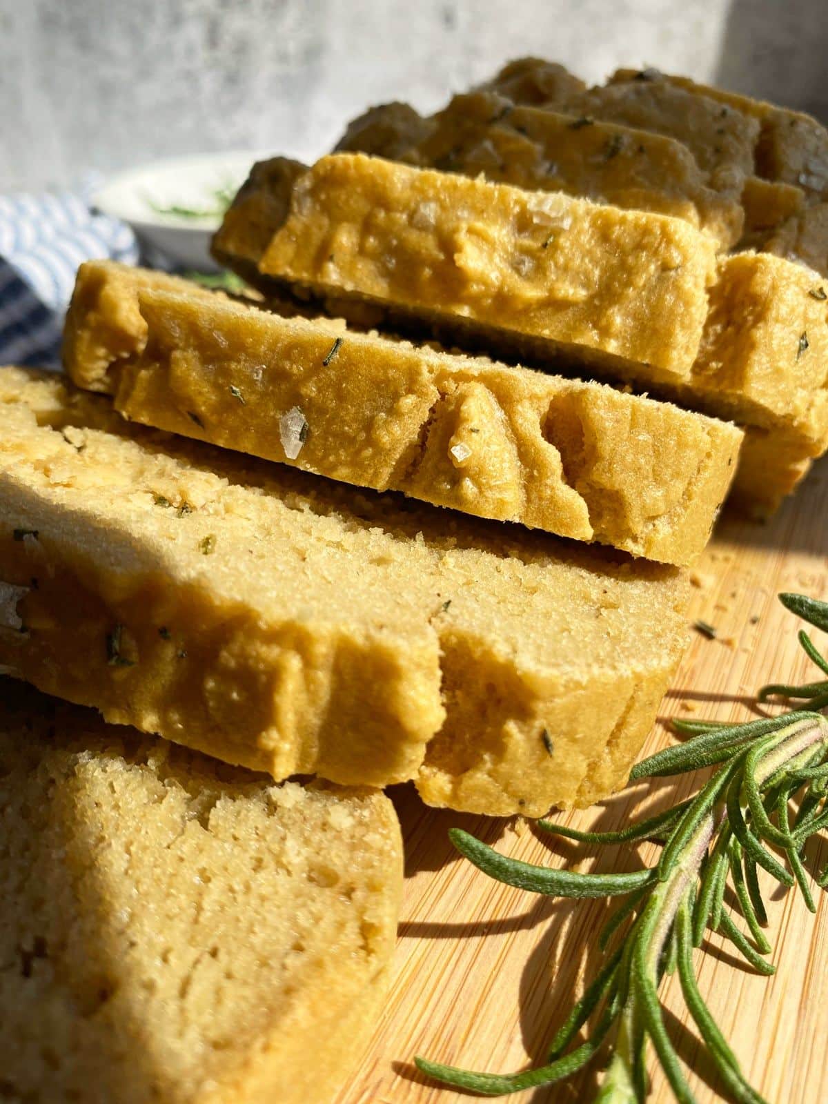 Sliced Cassava Flour Rosemary Bread on a wooden cutting board.