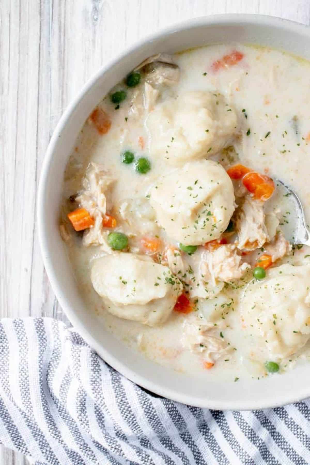 Gluten-Free Chicken and Dumplings in a white bowl with a spoon.