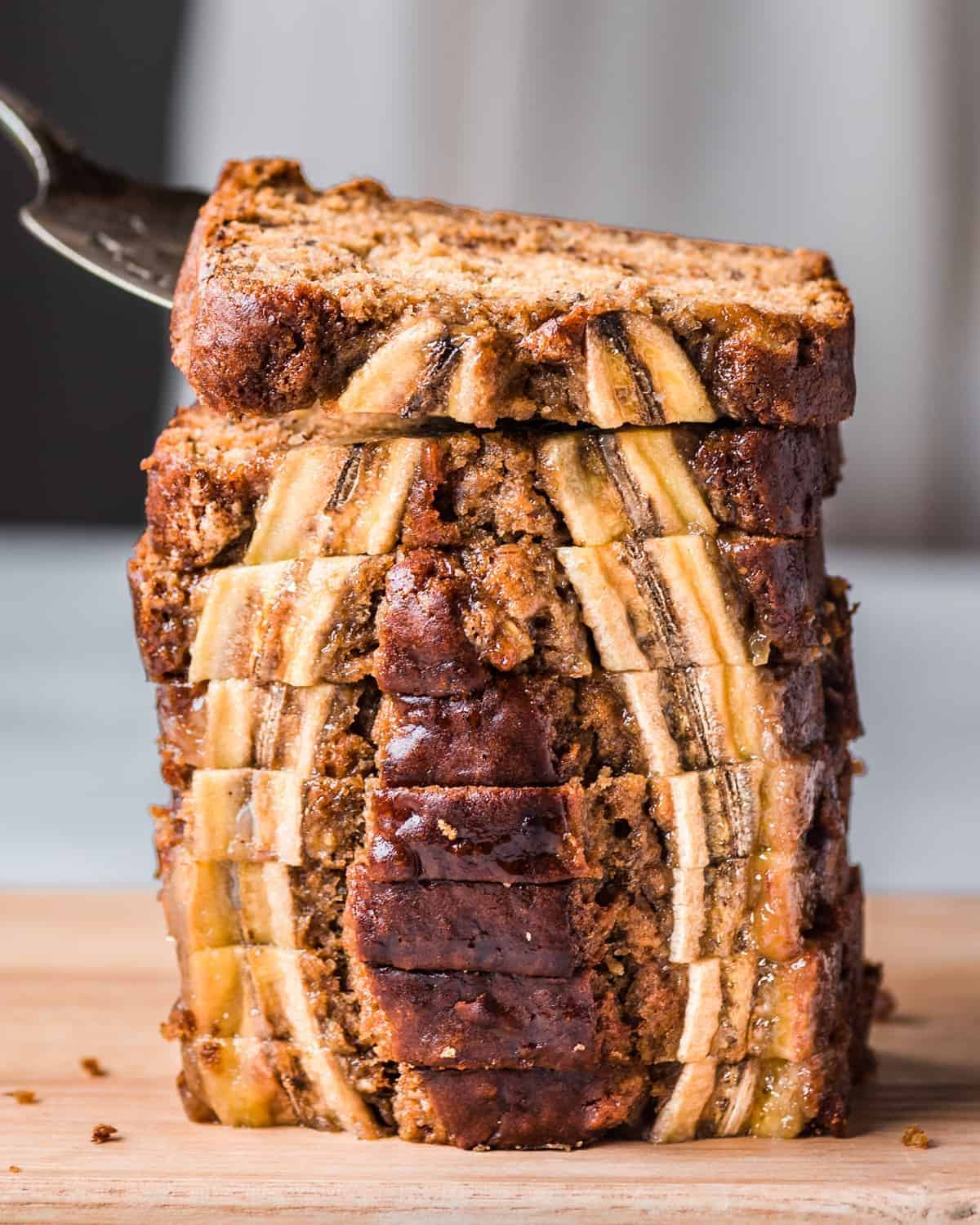 A pile of Vegan Banana Bread slices on a wooden tray.