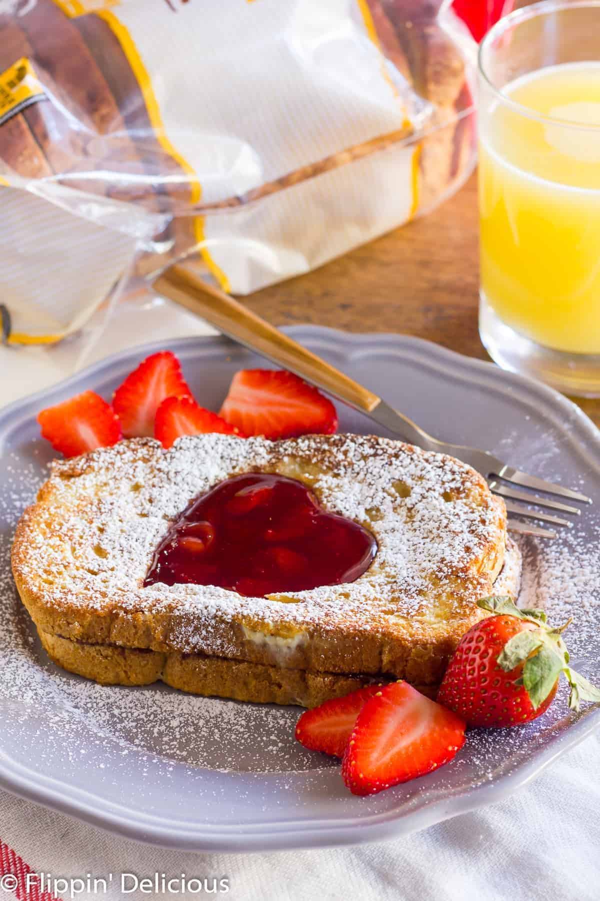 Flavorful Gluten-Free Nutella Stuffed French Toast on a gray plate with a fork and sliced strawberries.