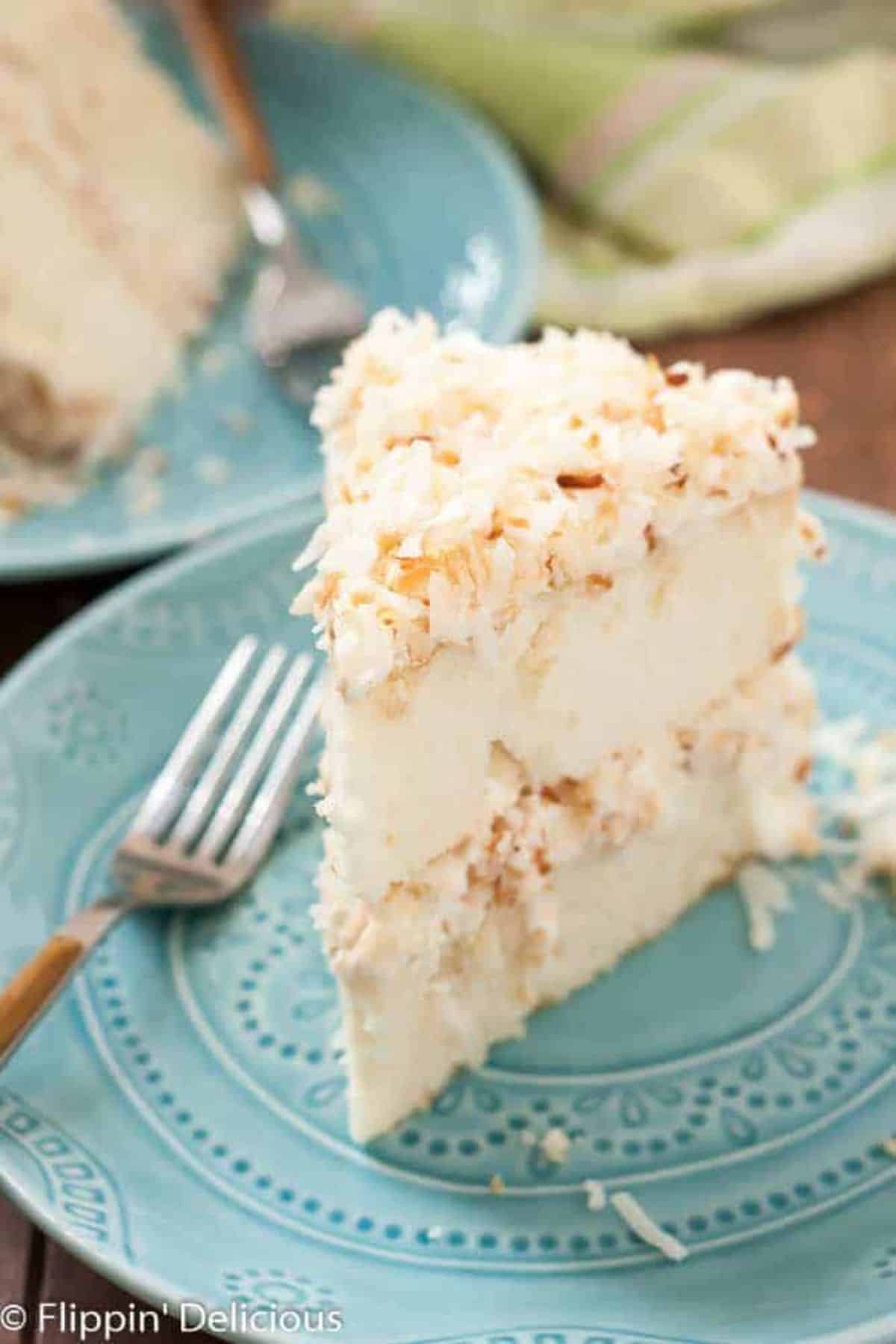 A piece of Coconut Layer Cake on a blue plate with a fork.