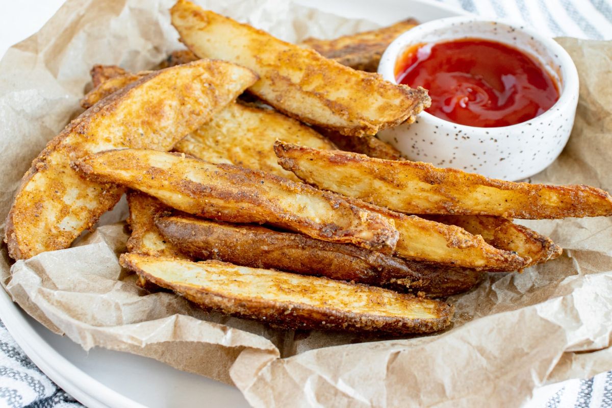 Crispy Oven-Baked Potato Wedges with a bowl of dip on a tray.