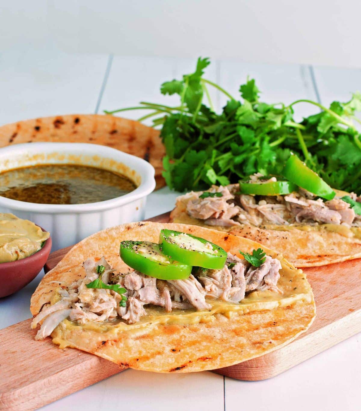 Mouth-watering Instant Pot Tomatillo Pork Tacos on a wooden cutting board.