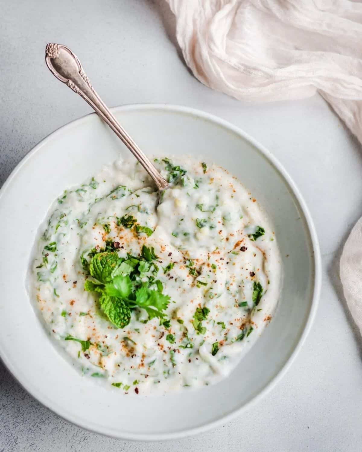 Creamy gluten-free Vegan Raita on a white plate with a spoon.