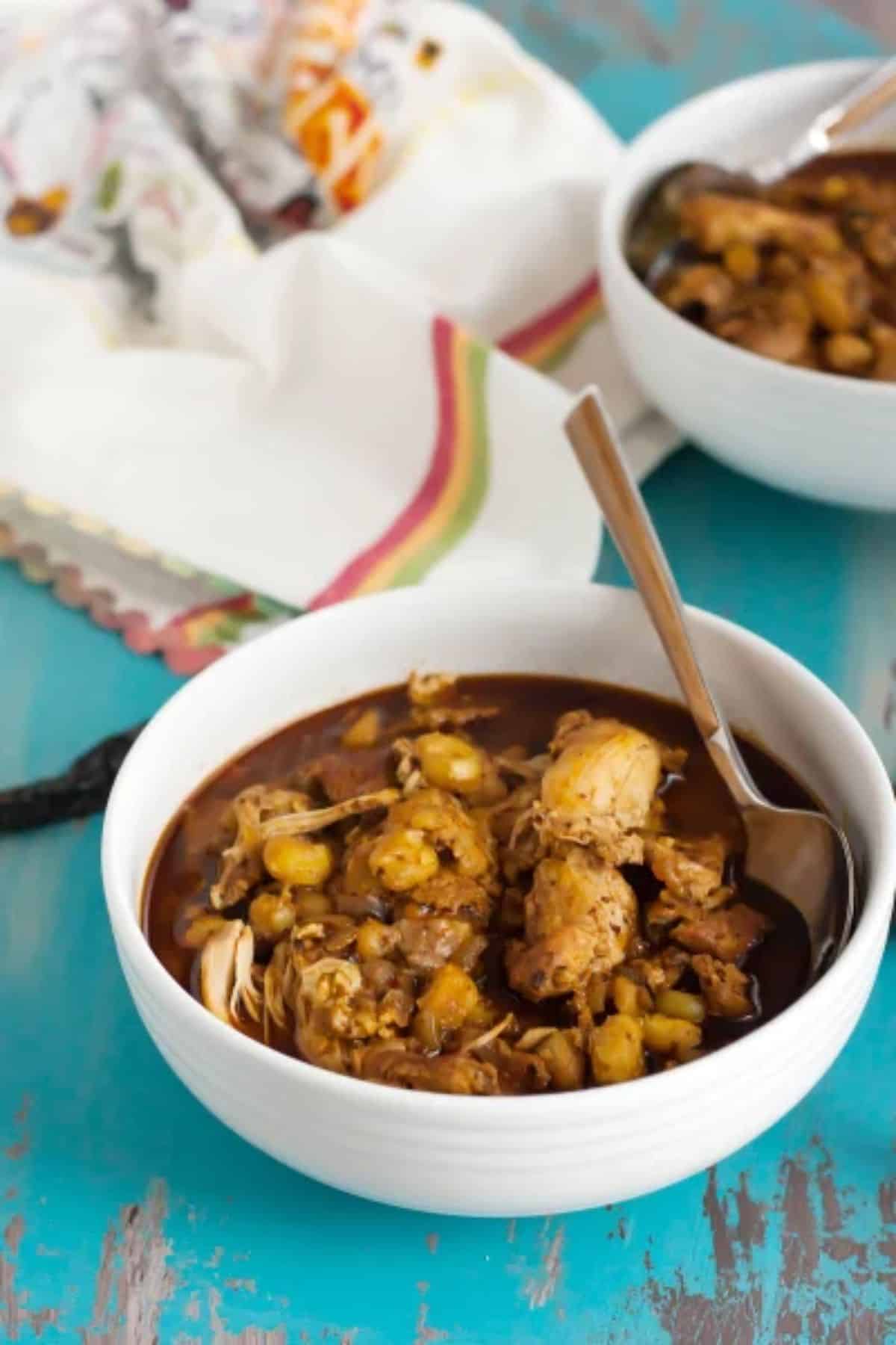 Delicious Chicken Posole in a white bowl with a spoon.