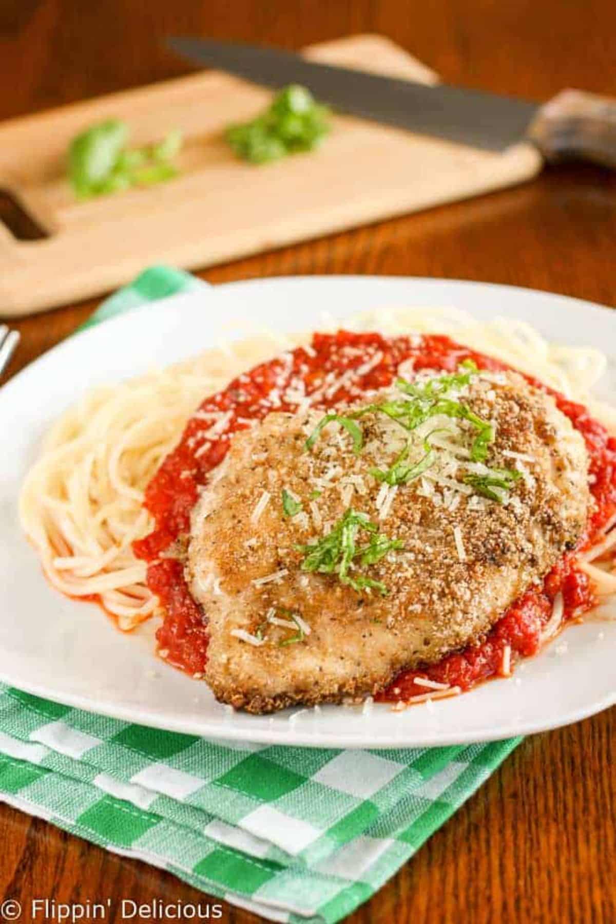 Crispy Gluten-Free Chicken Parmesan with pasta and sauce on a white plate.