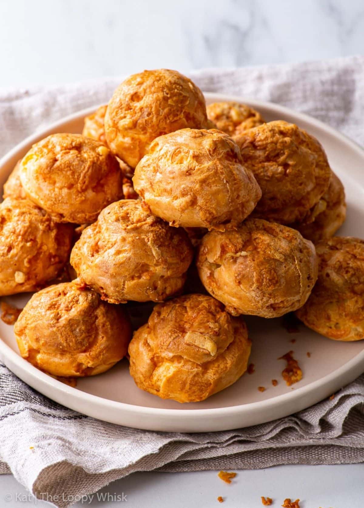 A pile of crispy French Cheese Puffs on a pink tray.