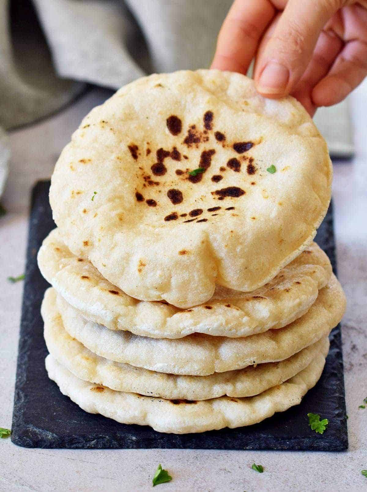 A pile of delicious Pita Bread on a black tray.