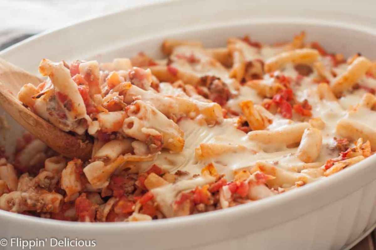 Juicy Dairy-Free Gluten-Free Baked Ziti in a white casserole scooped by a wooden spoon.