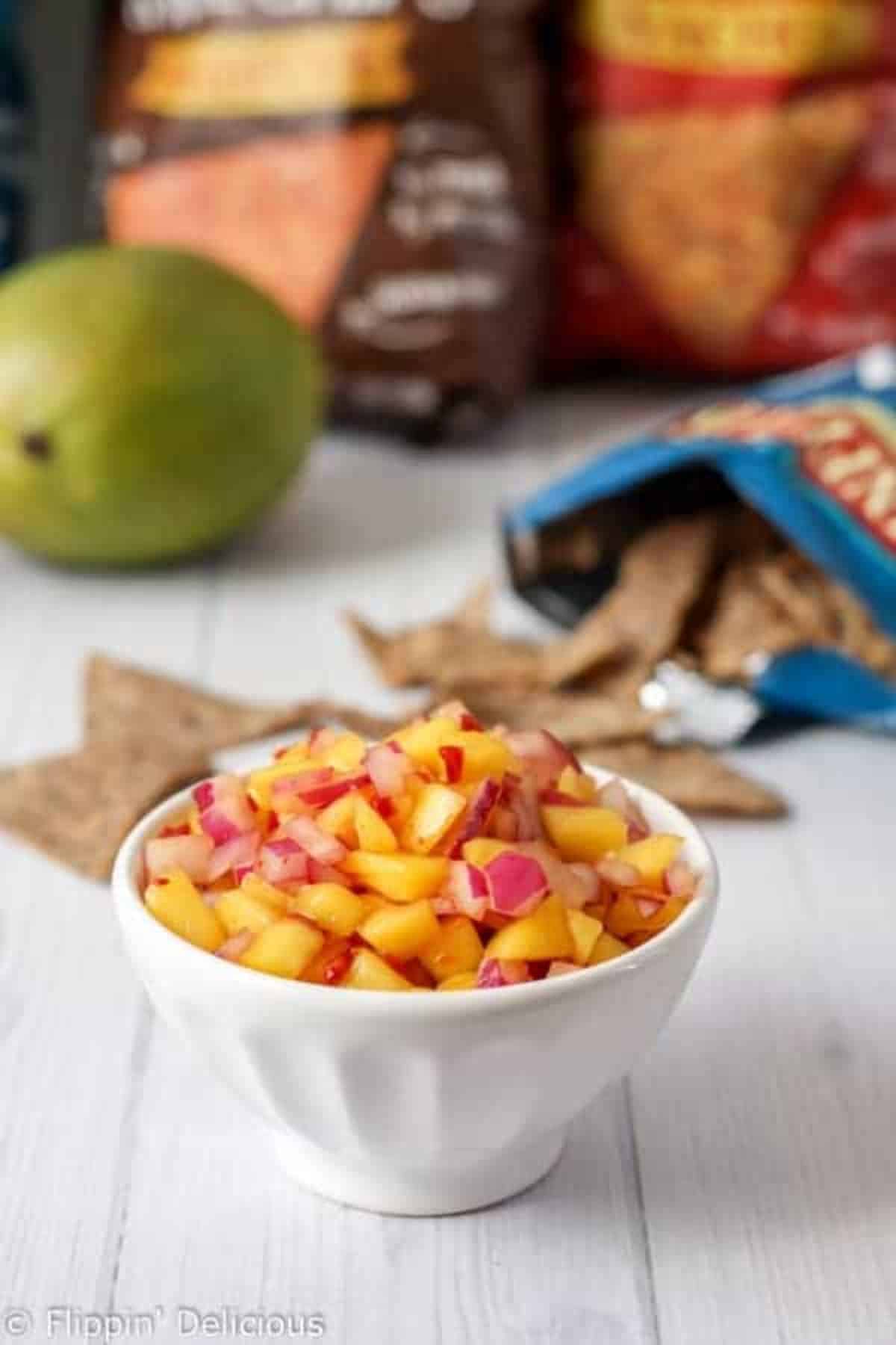 Healthy Chipotle Mango Salsa with Vegan Nachos in a white bowl.