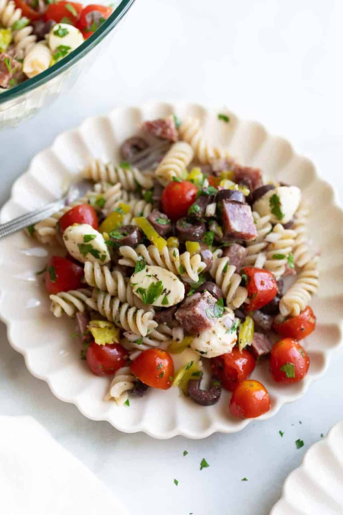 Healthy Gluten-Free Italian Pasta Salad on a white plate with a fork.