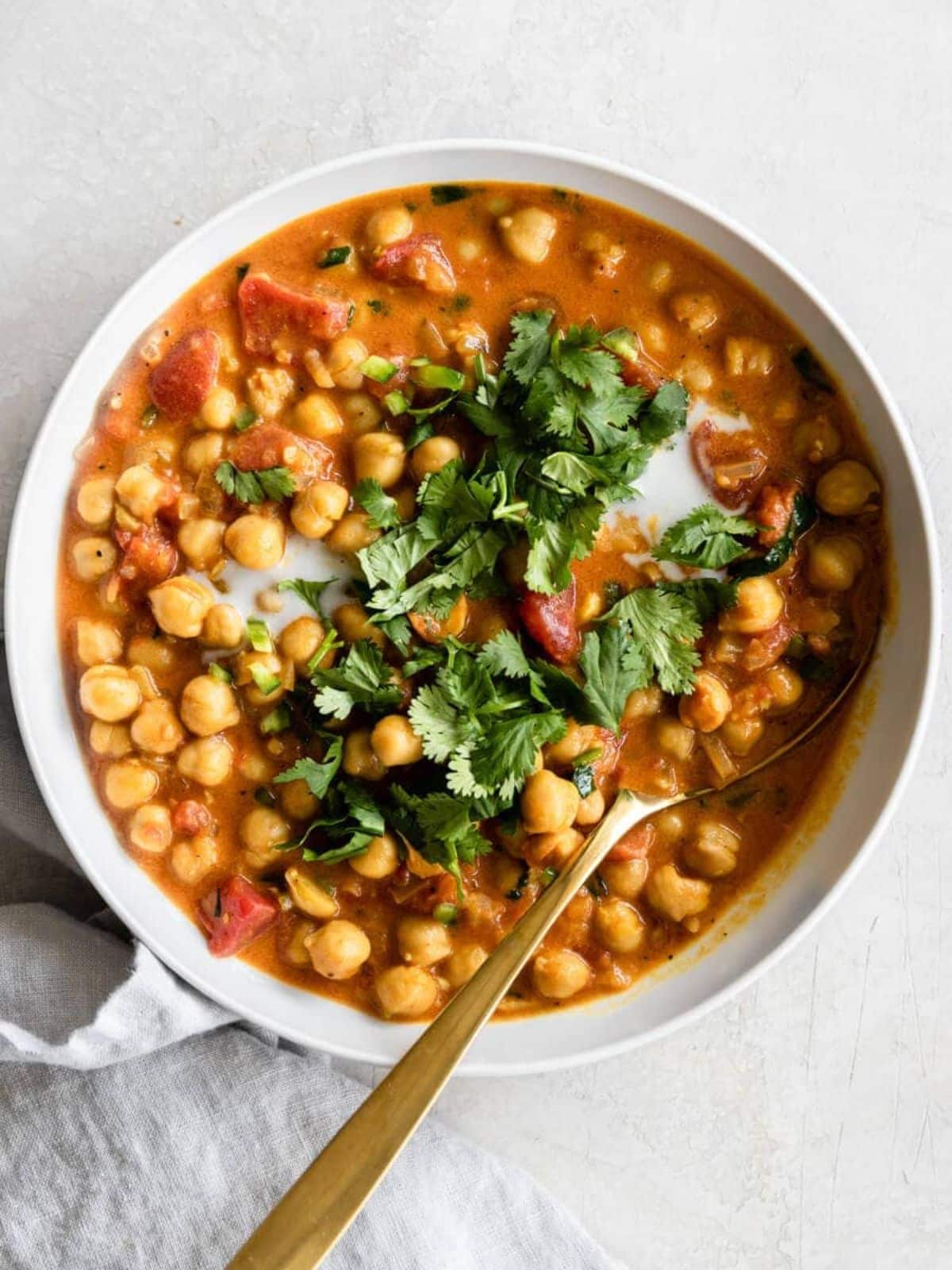 Flavorful Coconut Chickpea Curry in a white bowl with a spoon.