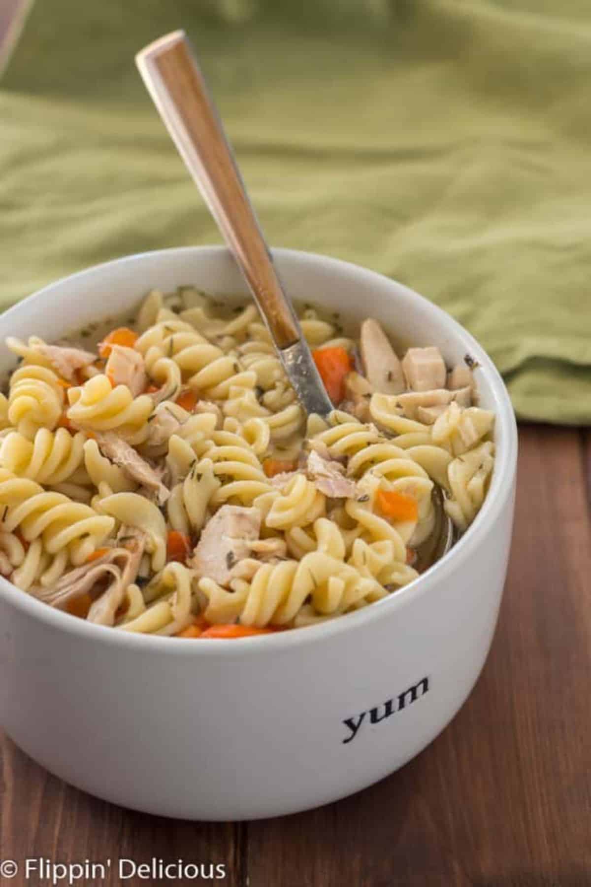 Flavorful Instant Pot Gluten-Free Chicken Noodle Soup in a white bowl with a spoon.
