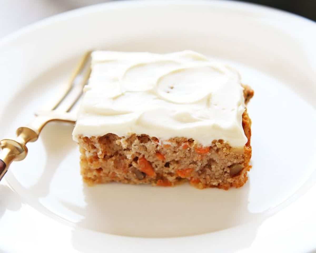 A piece of mouth-watering Healthy Carrot Cake on a white plate with a fork.
