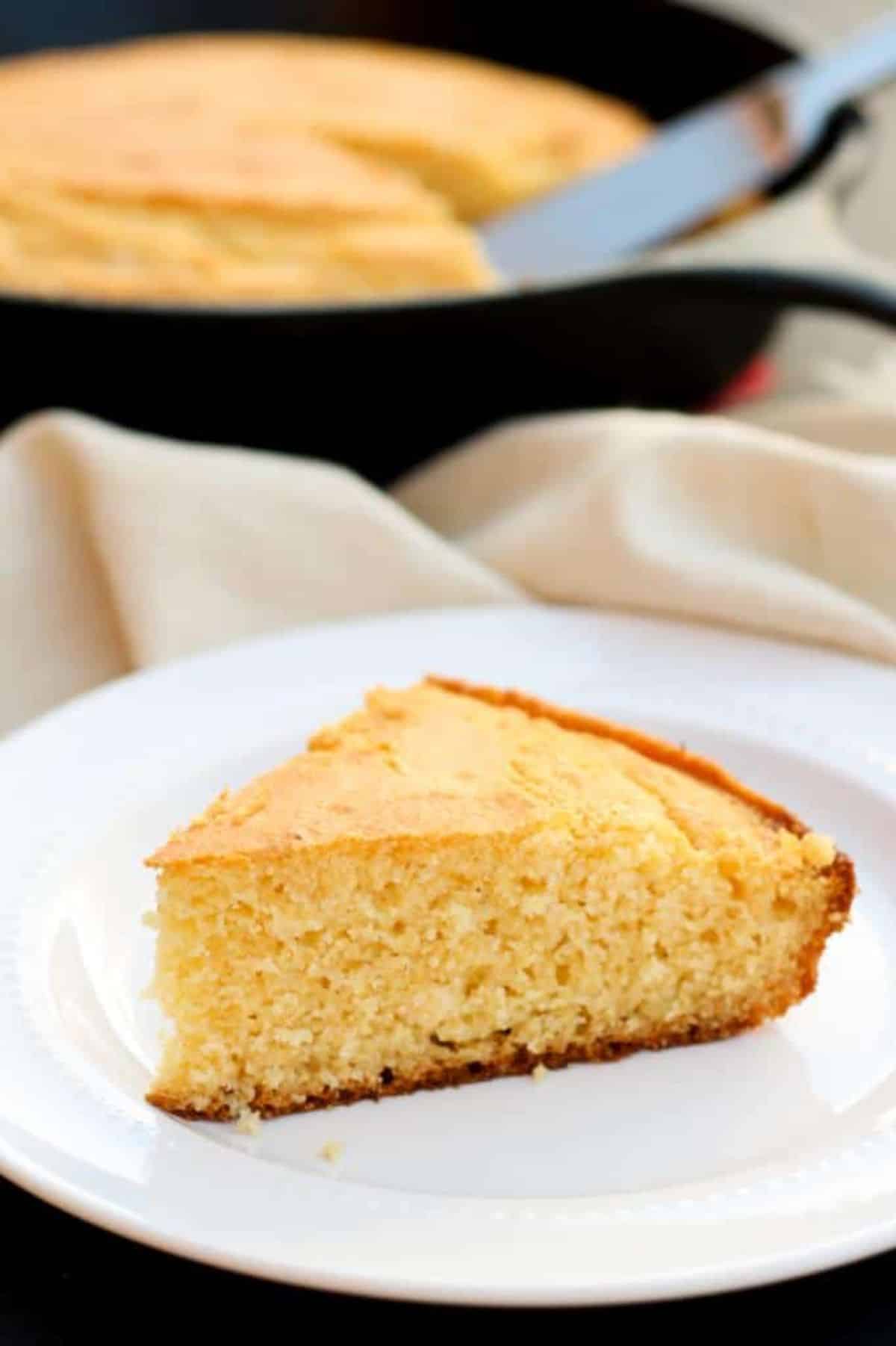 A piece of Gluten-Free Cornbread With Honey on a white plate.