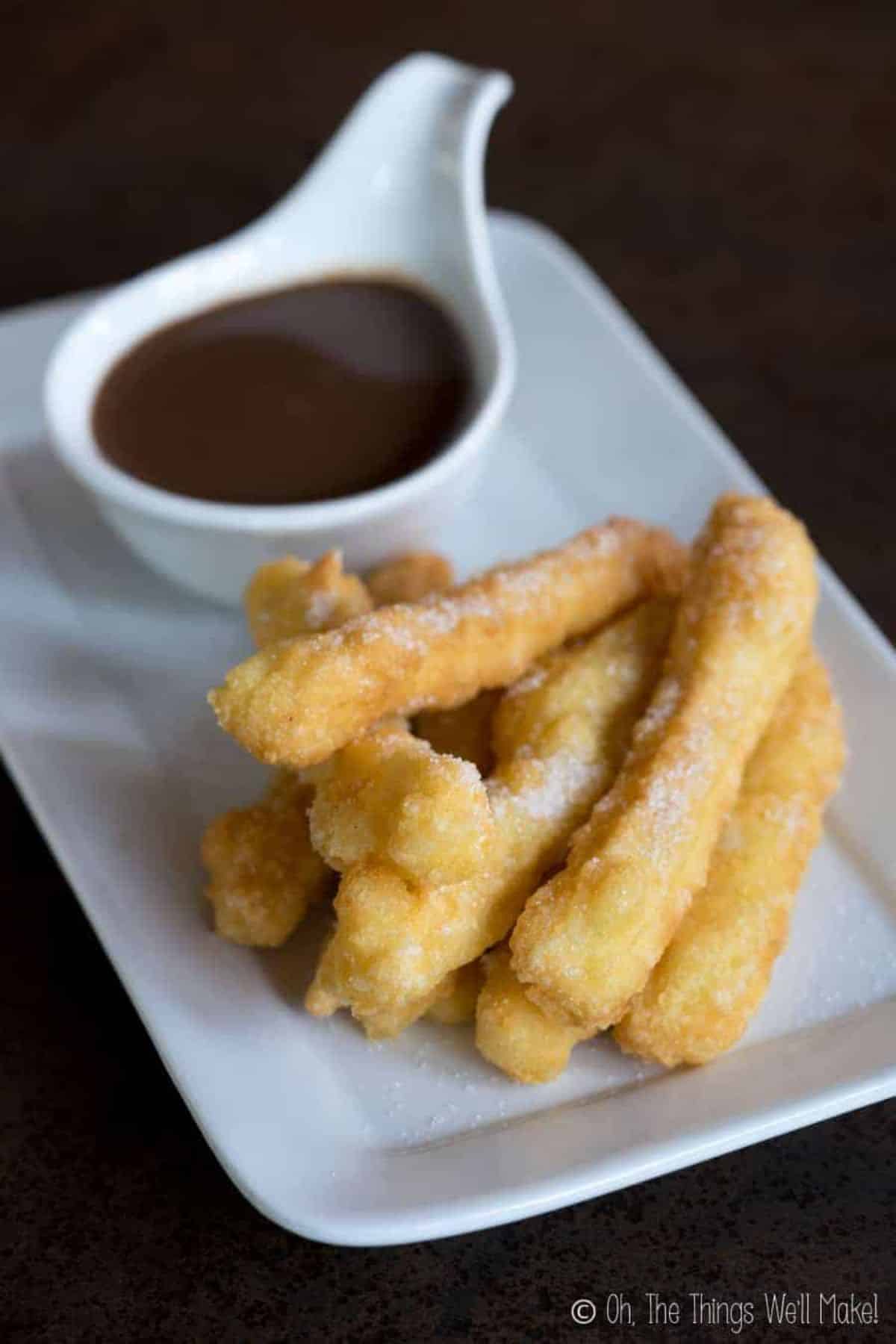 Crispy Tapioca Flour Churros with a bowl of dip on a white plate.