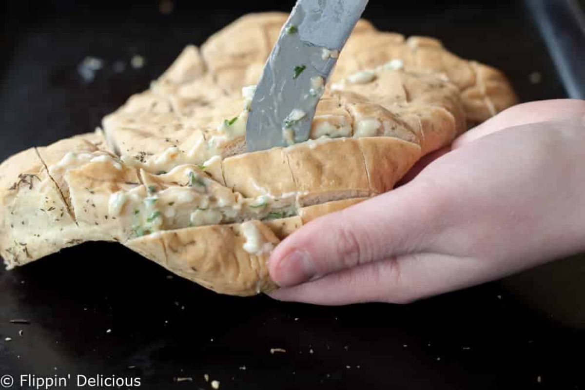 Gluten-Free Cheesy Garlic Pull-Apart Bread held by hand,