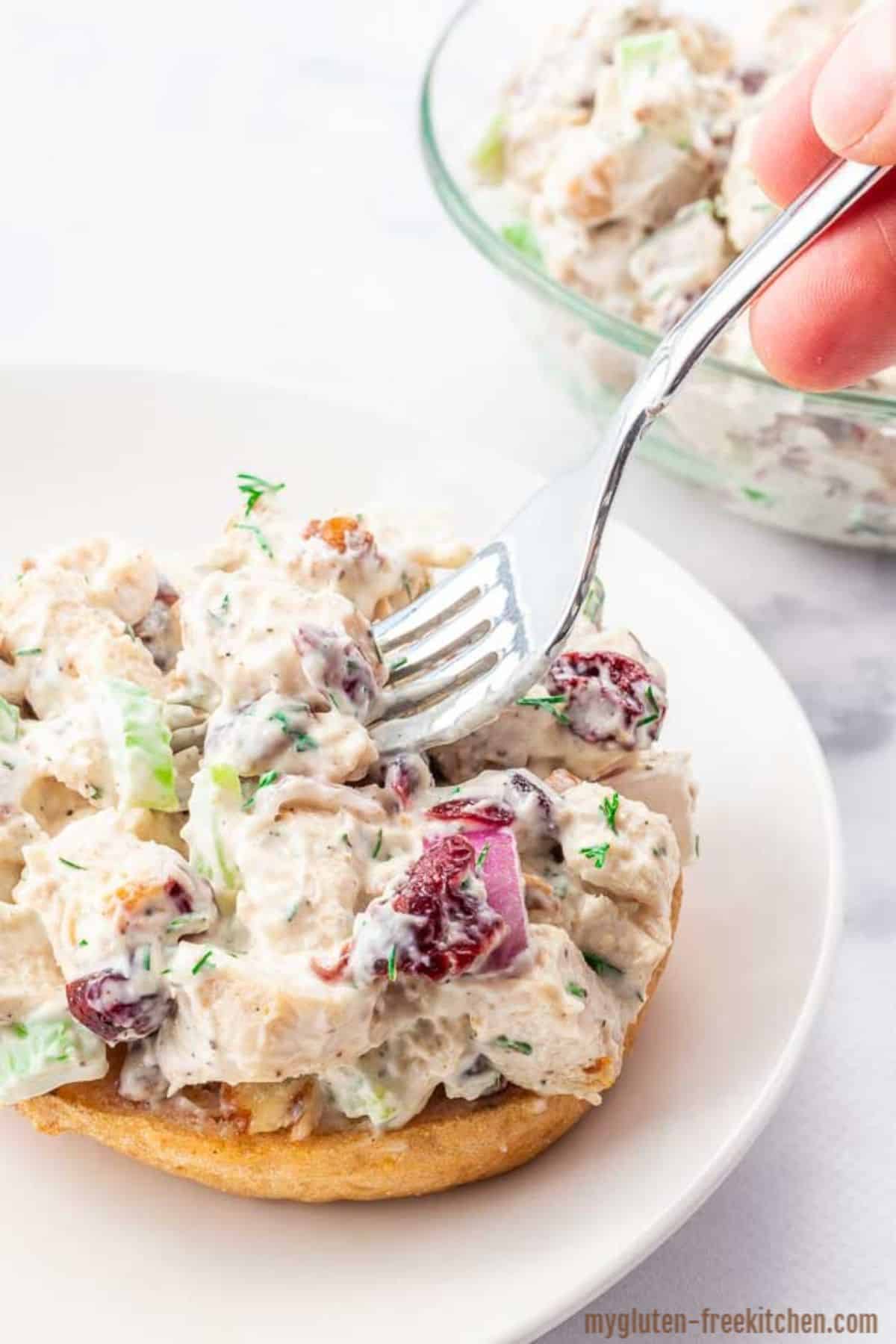 Delicious Chicken Salad on a burger bun picked by a fork.