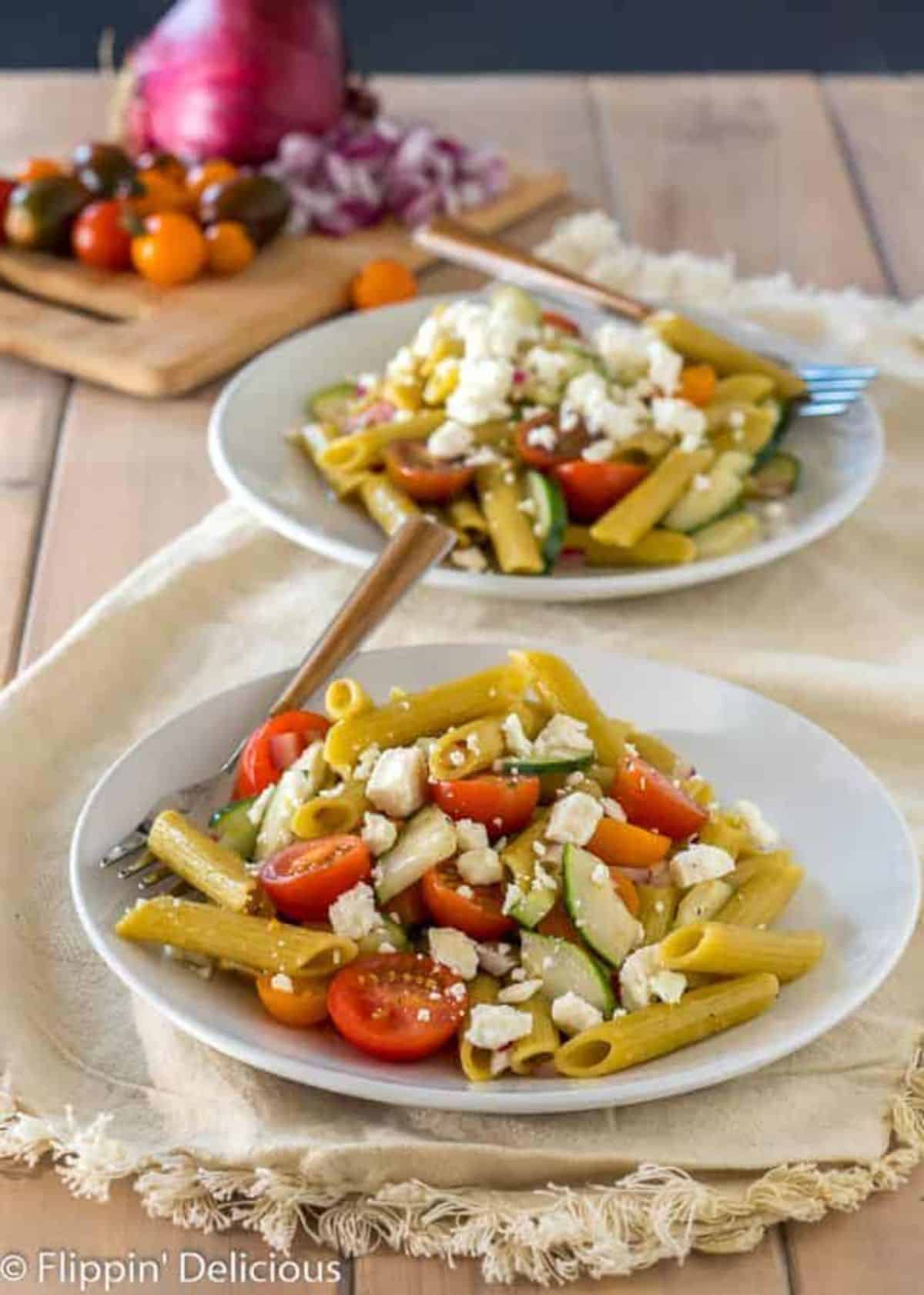 Healthy Gluten-Free Greek Pasta on two white plates on a wooden table.