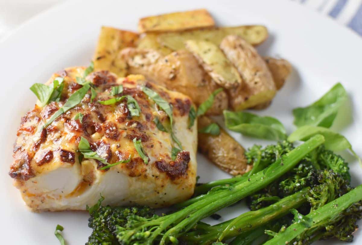 Delicious Mediterranean Baked Halibut with veggies on a white plate.