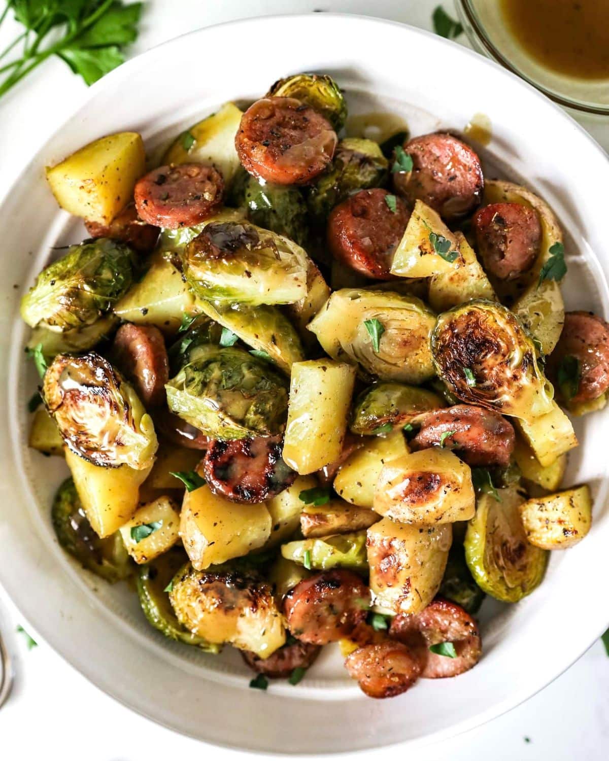 Healthy Sausage, Potatoes, and Brussels Sprouts in a white bowl.