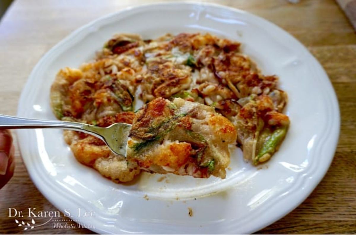 Scrumptious Korean Style Paleo Seafood Pancakes on a white plate and picked on a fork.