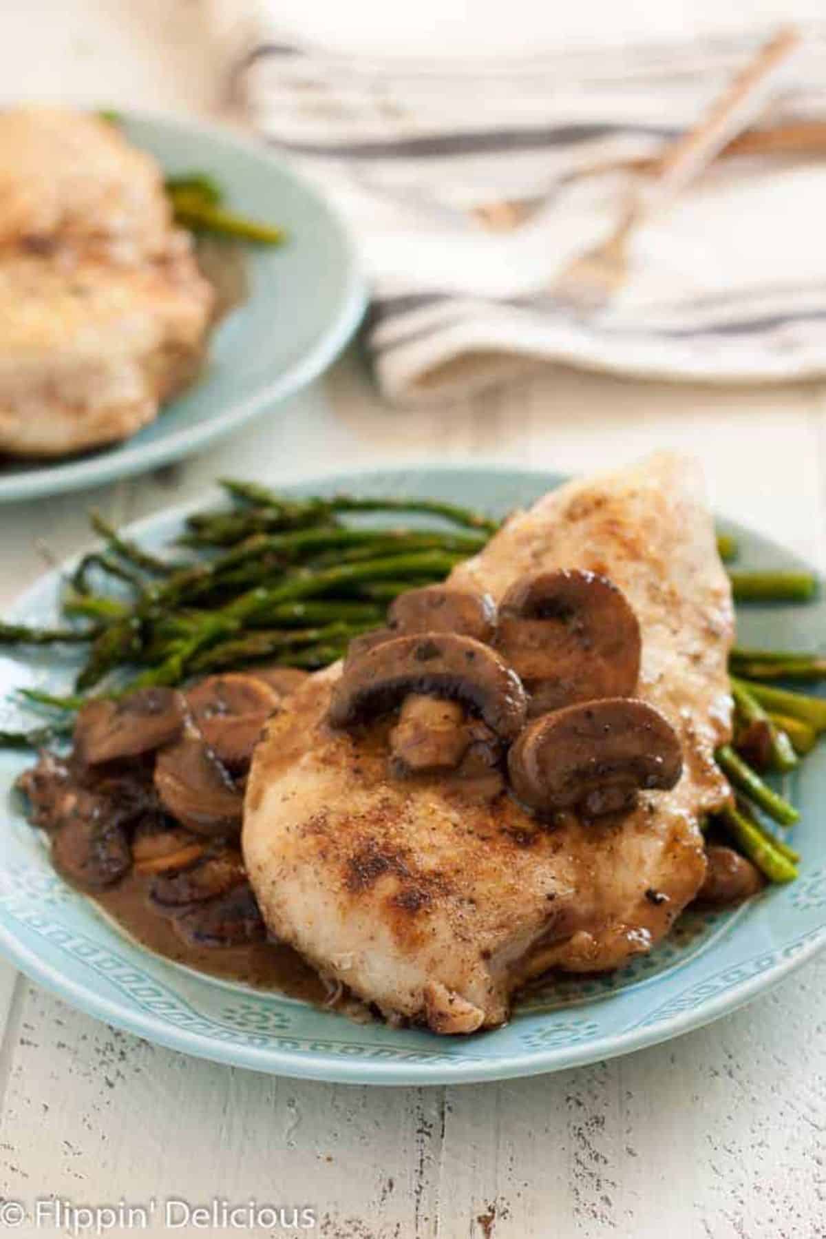 Tasty Gluten-Free Chicken Marsala with Mushrooms and asparagus on a blue plate.