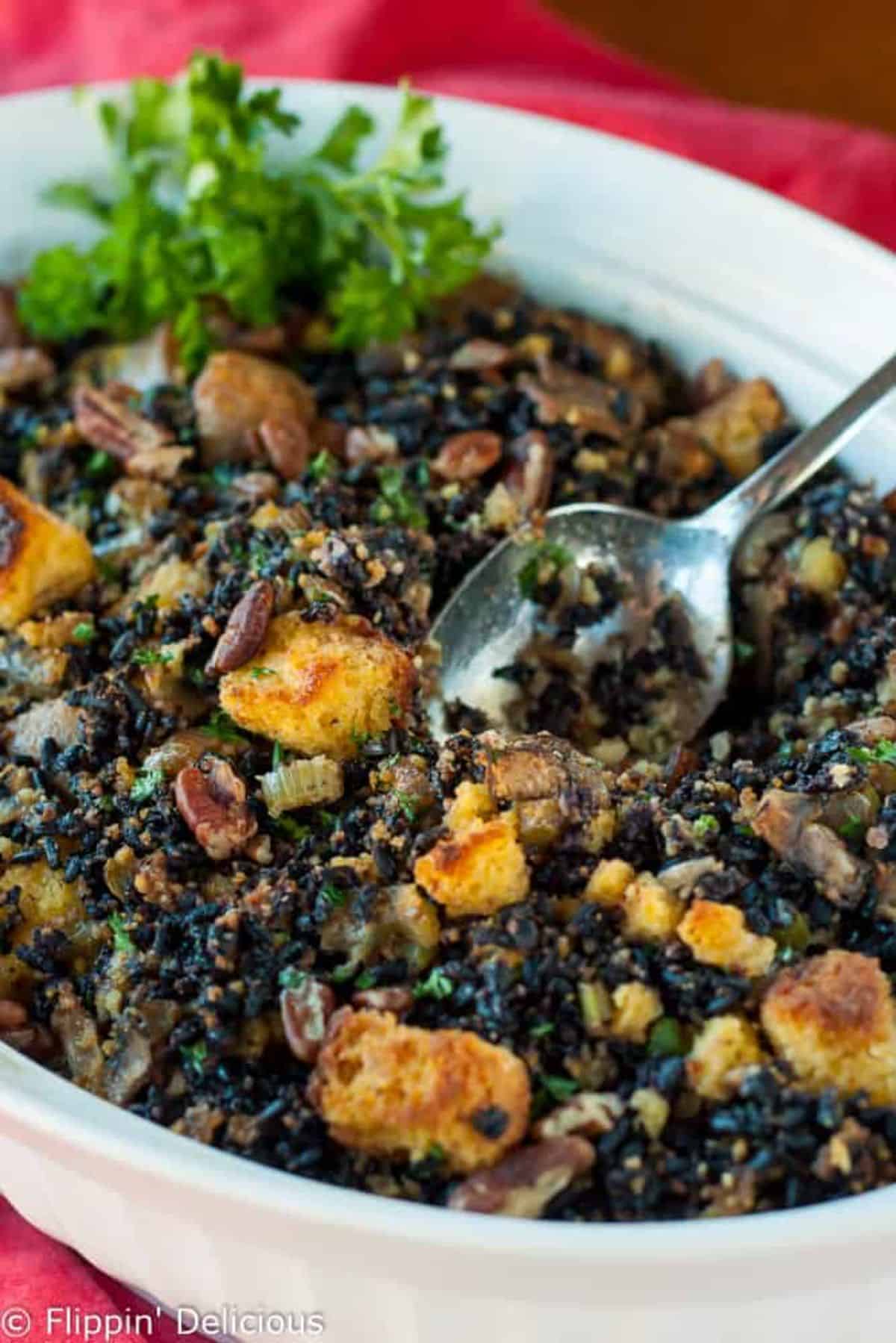 Tasty Gluten-Free Cornbread with Wild Rice, Sausage, and Pecans in a white casserole with a spoon.