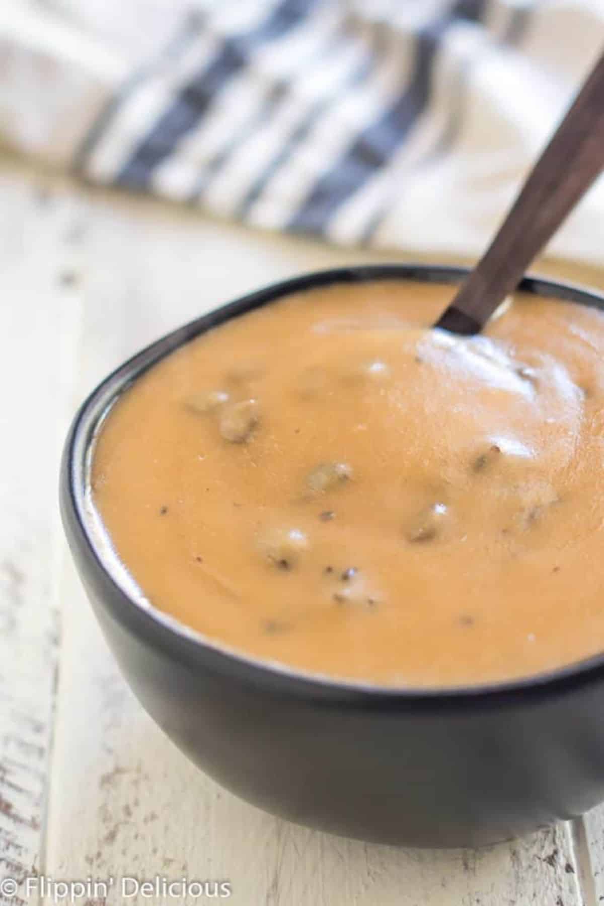 Tasty Gluten-Free Cream of Mushroom Soup in a black bowl with a spoon.