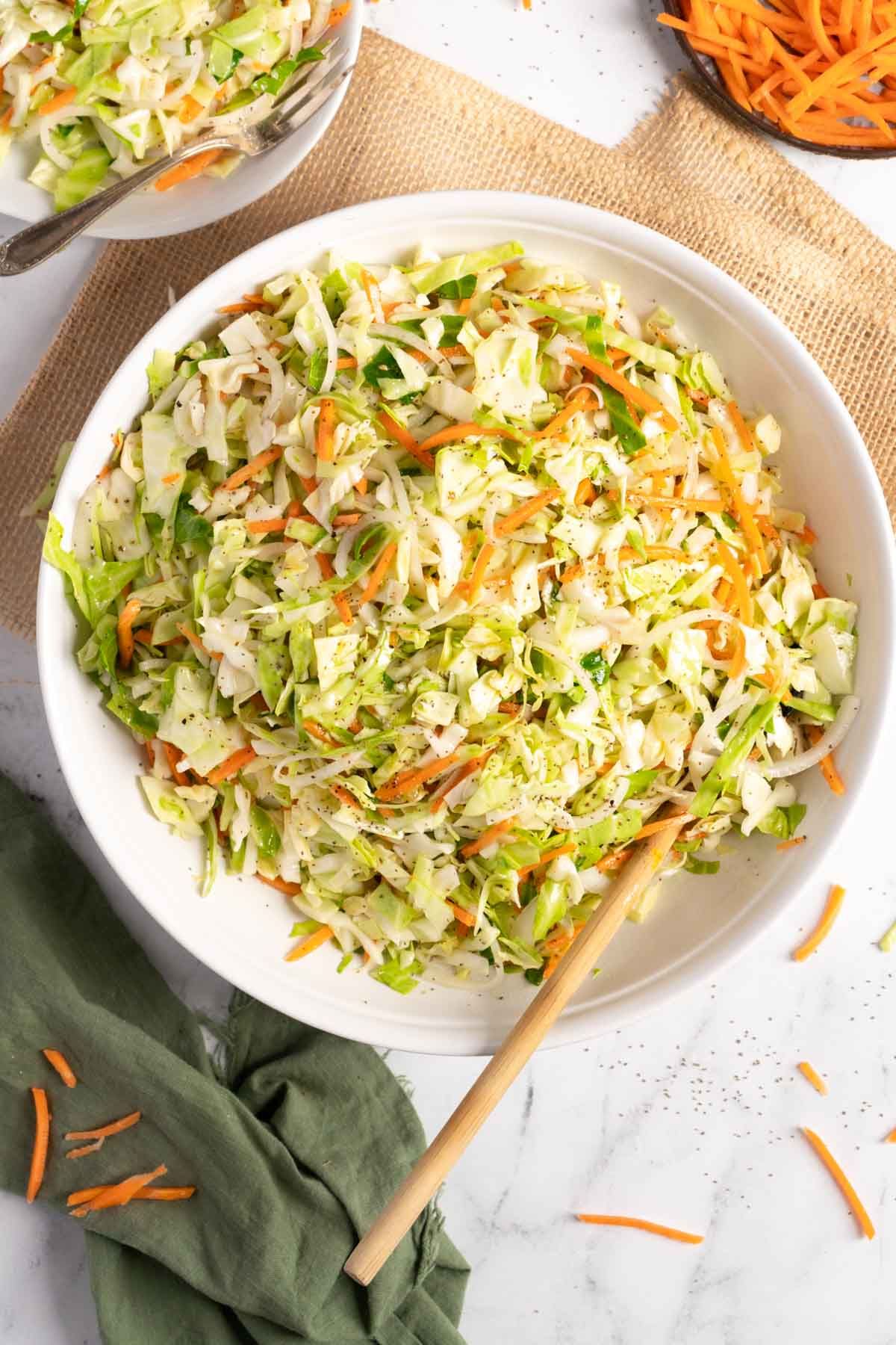 Flavorful Old-Fashioned Coleslaw With Vinegar in a white bowl with a wooden spoon.