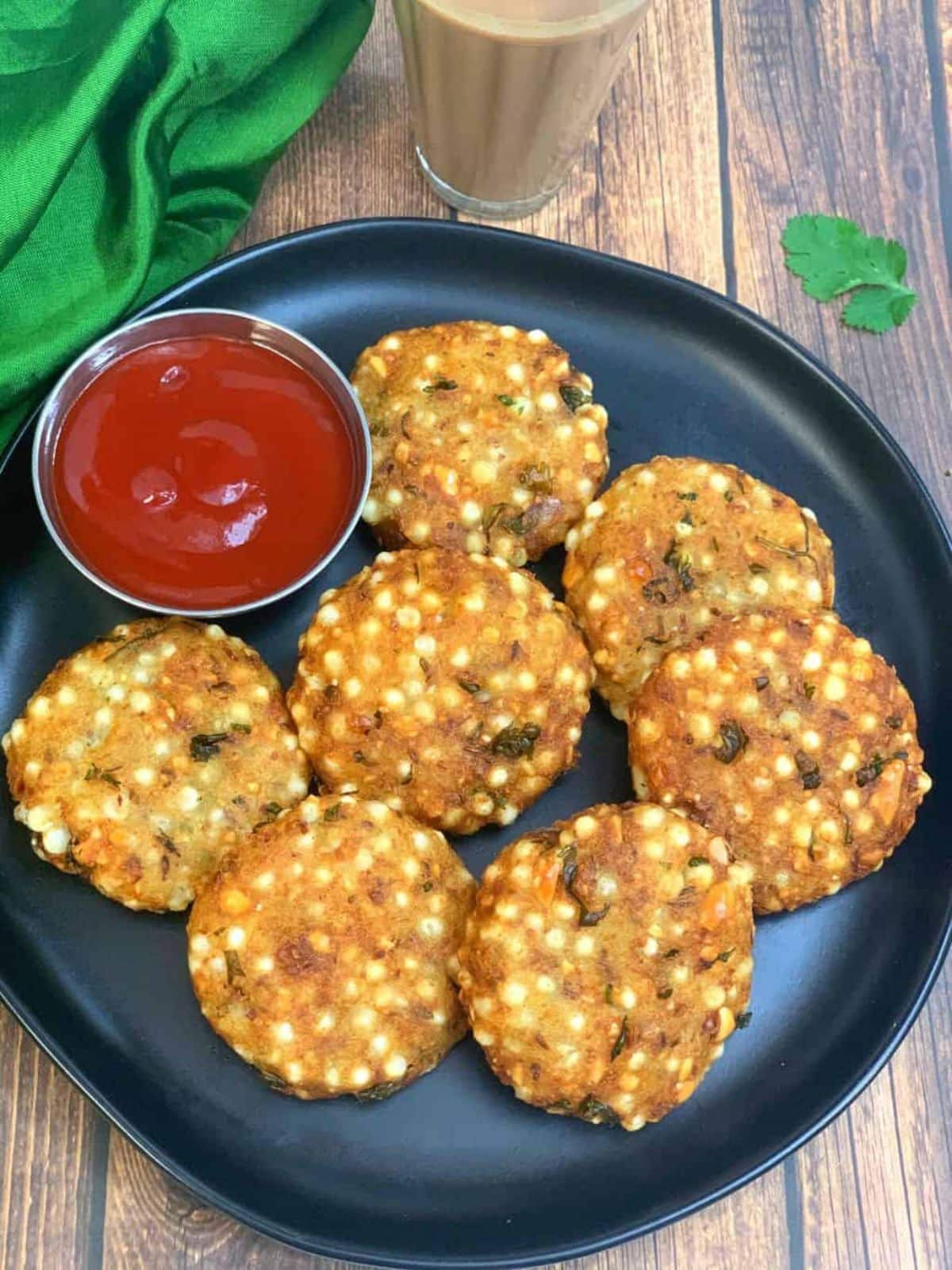 Crunchy gluten-free Sabudana Vada with a bowl of dip on a black plate.