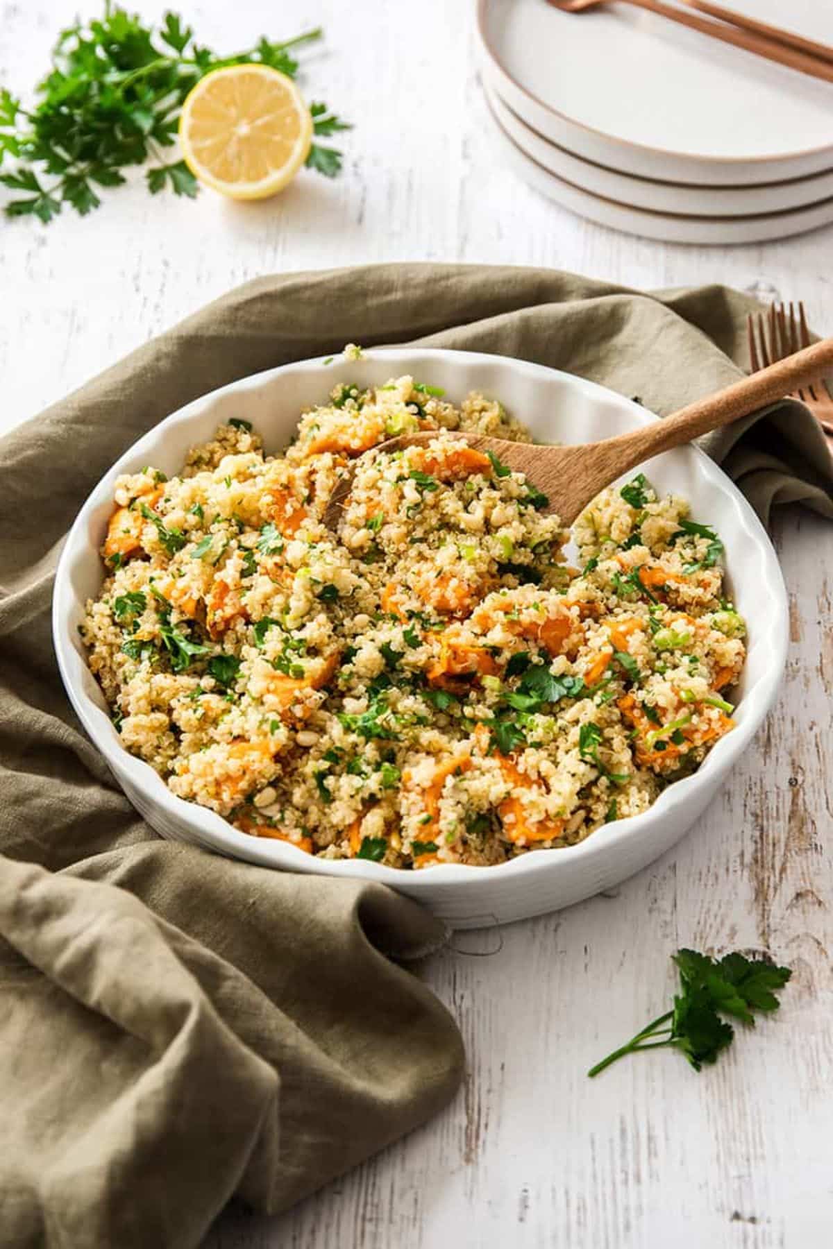 Healthy Sweet Potato Quinoa Salad in a white bowl with a wooden spoon.