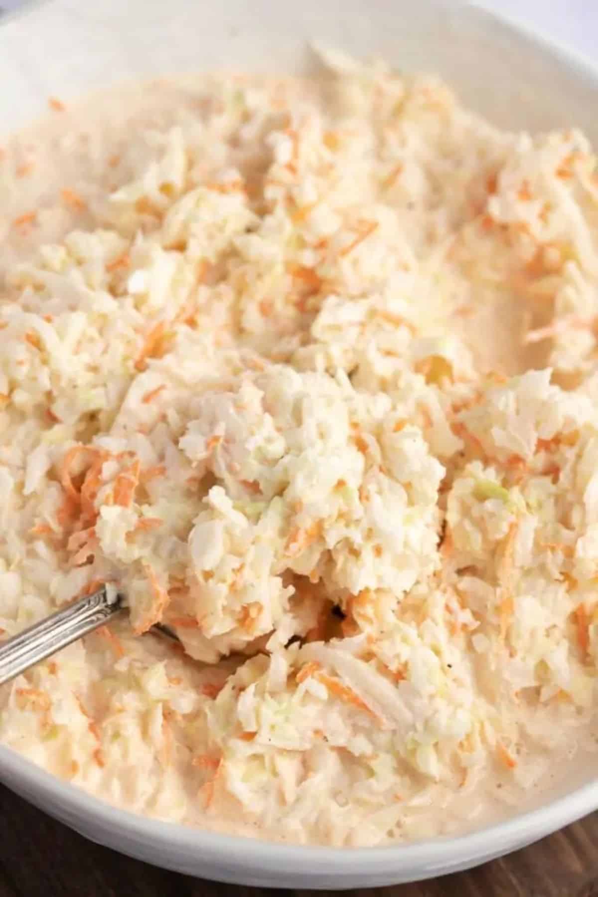 Delicious gluten-free KFC Coleslaw in a white bowl with a spoon.