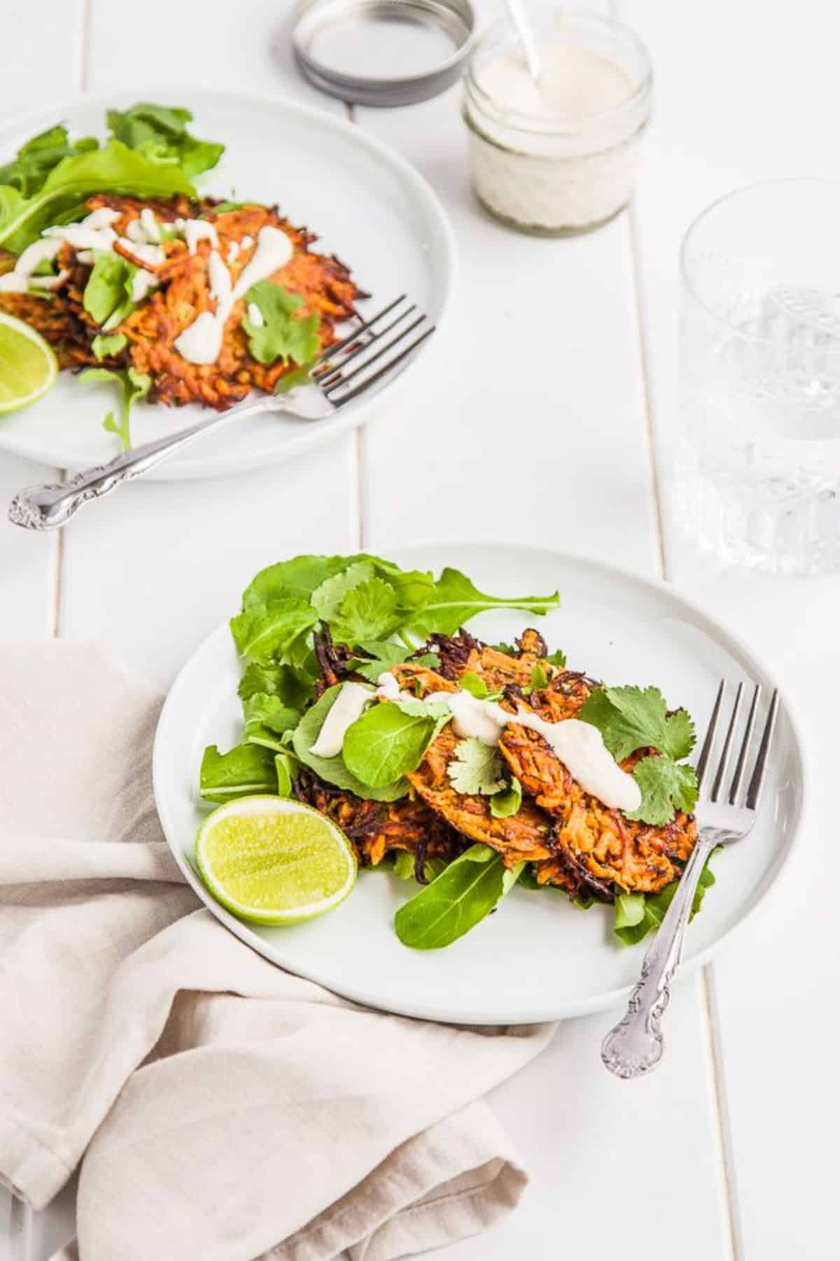 Delicious Sweet Potato Fritters with Cashew Lime Cream on a white  plate with a spoon.