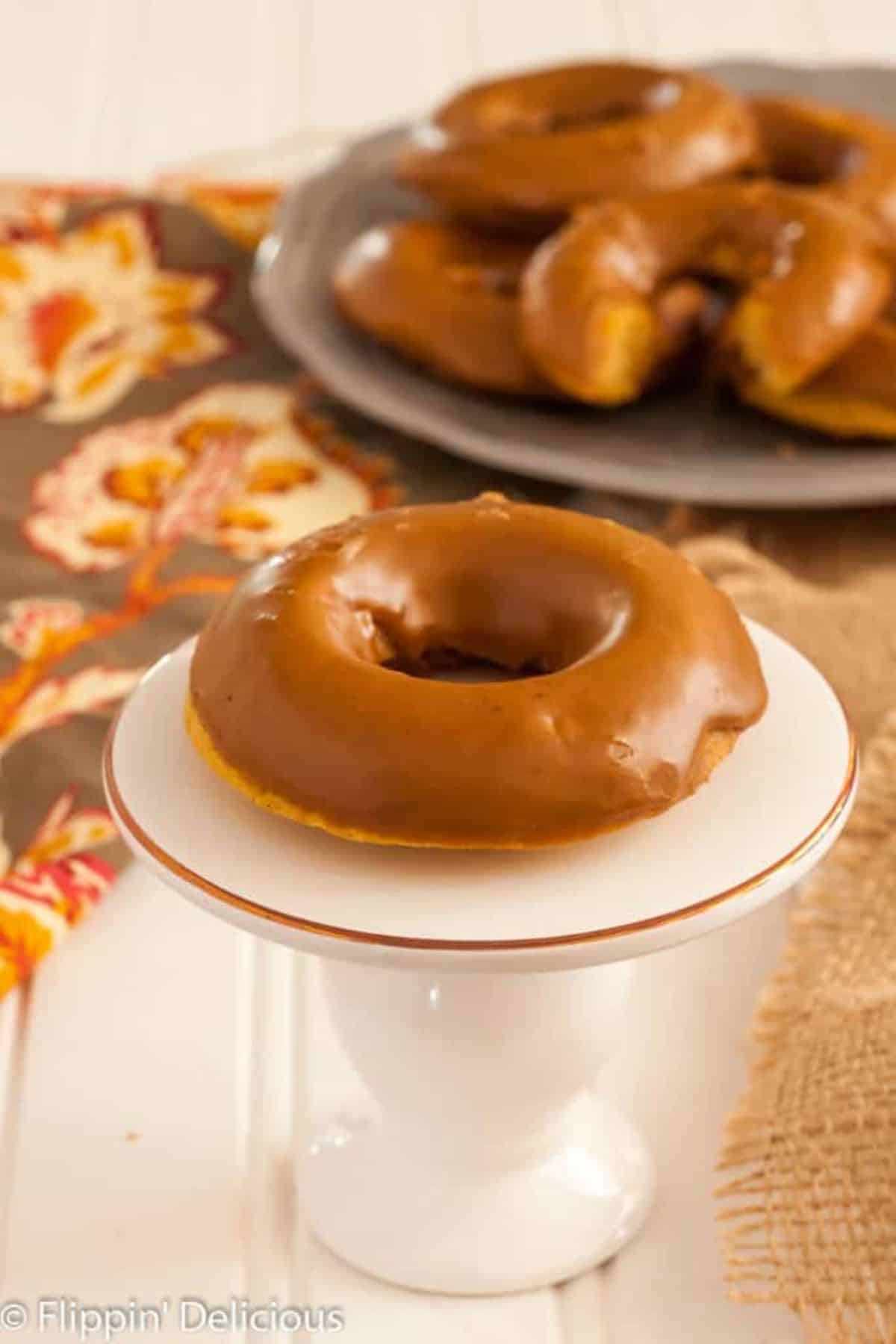 A mouth-watering Pumpkin Spice Latte Donut on a small cake tray.