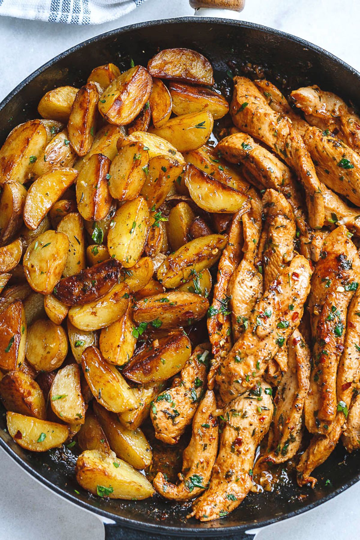 Juicy Garlic Butter Chicken and Potatoes in a black skillet.