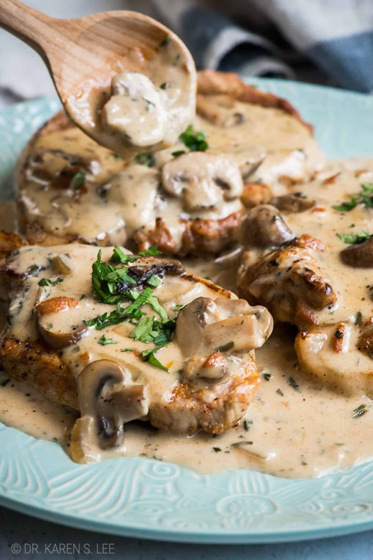 Juicy Pork Chops Smothered in Creamy Mushroom Sauce on a blue plate.