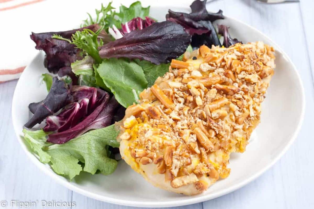 Crispy Gluten-Free Pretzel Chicken with Honey Mustard with salad on a white plate.