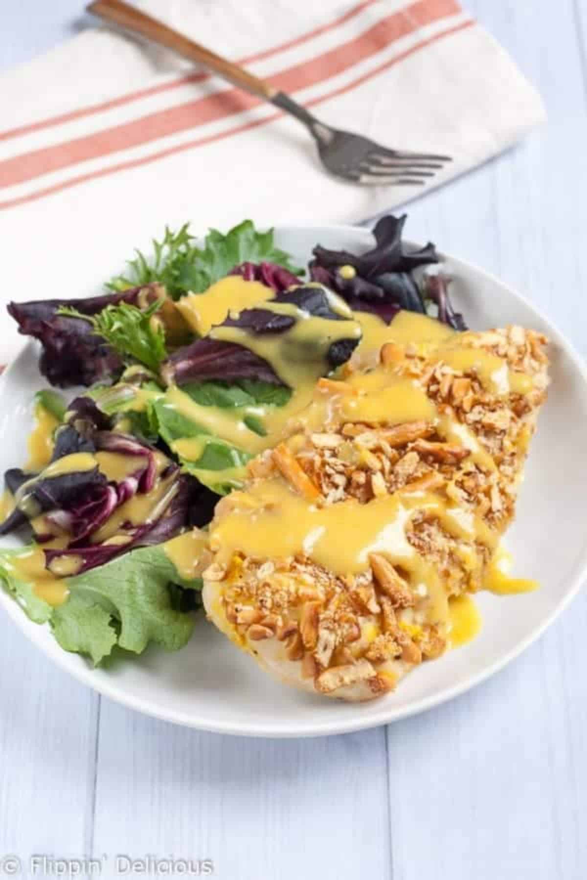 Crispy Gluten-Free Pretzel Chicken with Honey Mustard with veggies on a white plate.