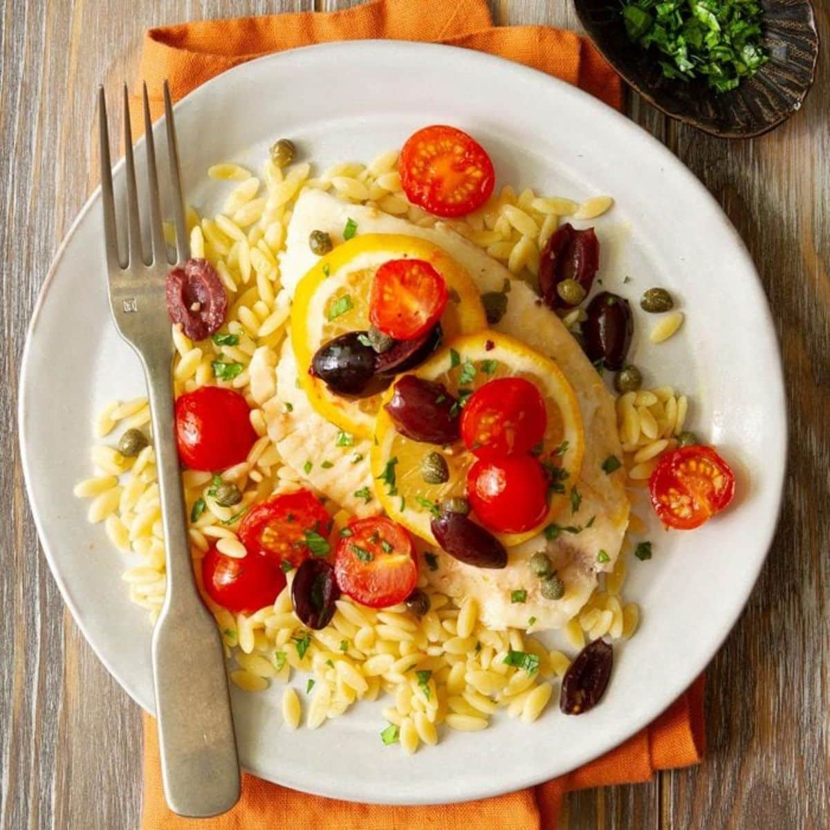 Flavorful gluten-free Mediterranean Sole on a white plate with a fork.