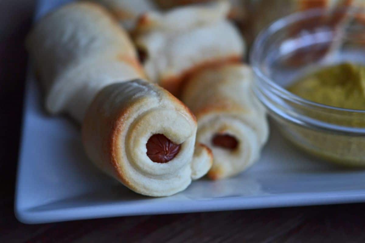Crunchy gluten-free Pigs in a Blanket on a white plate.