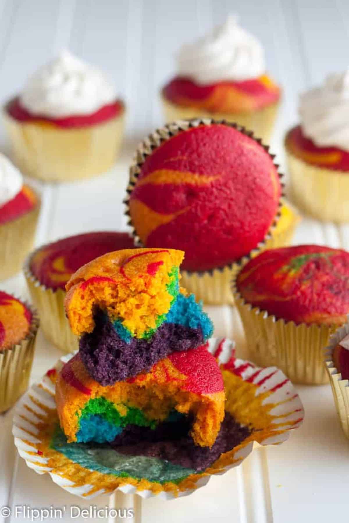 Mouth-watering Gluten-Free Rainbow Cupcakes o a wooden table.
