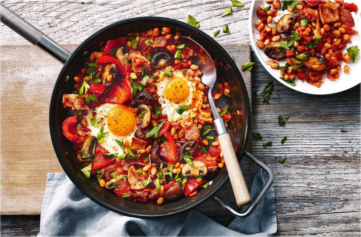 Scrumptious Breakfast Shakshuka on black skillet with a spoon.