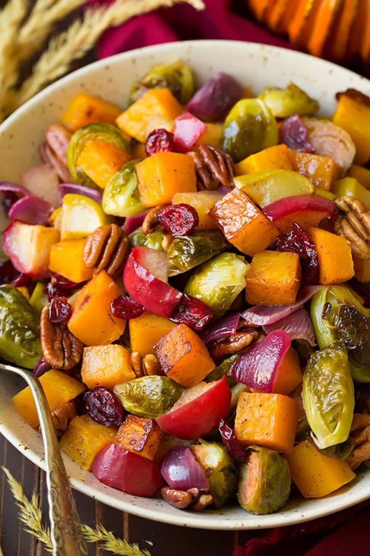 Healthy Autumn Roasted Vegetables With Apples and Pecans in a white bowl.