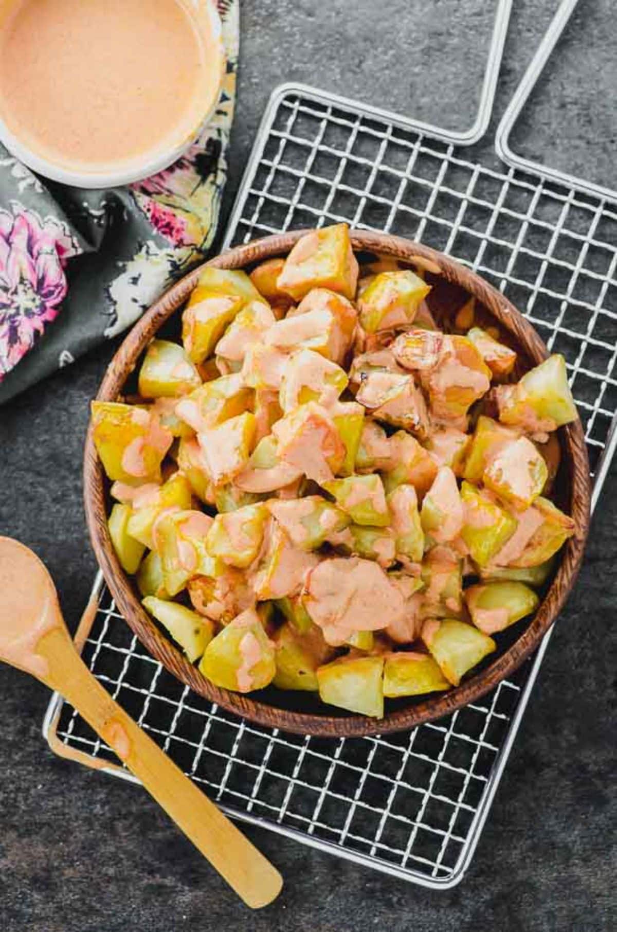 Tasty Patatas Bravas in a wooden bowl.