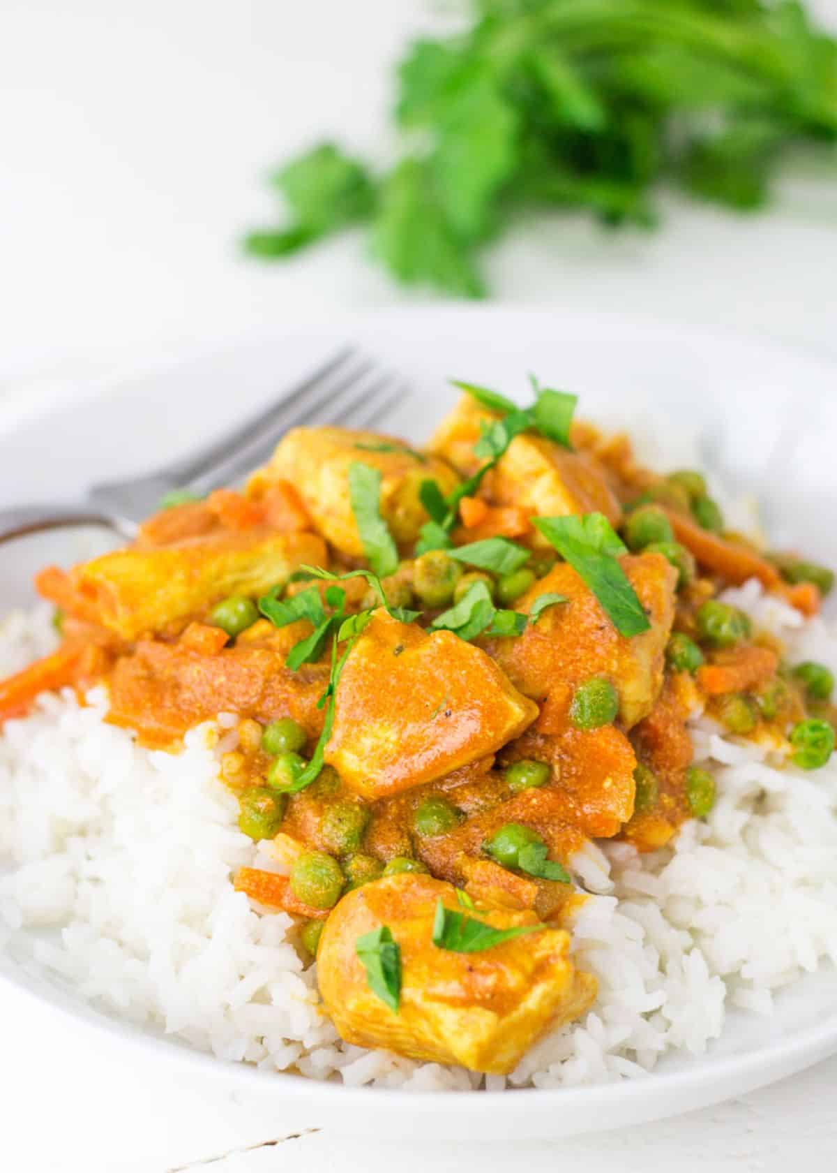 Healthy Gluten-Free Chicken Tikka Masala on a white plate with a fork.