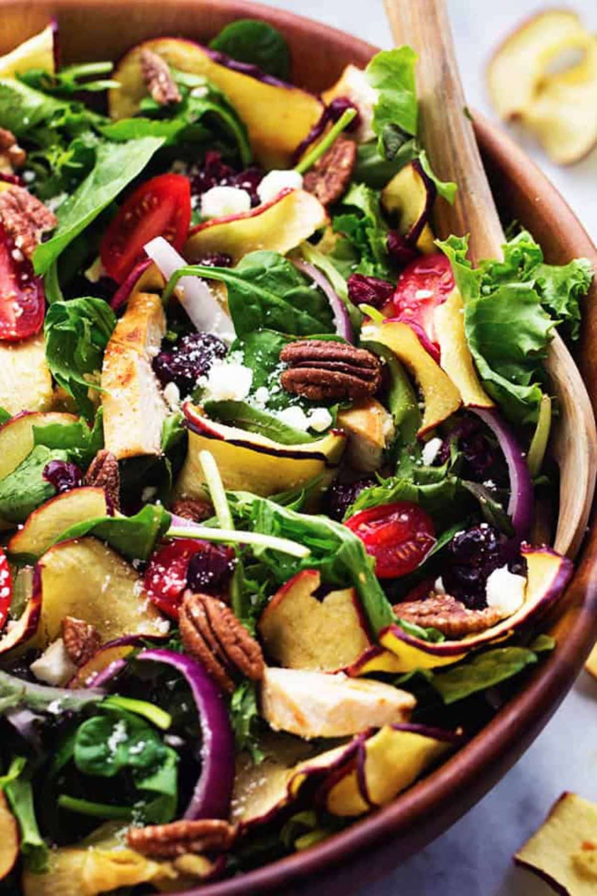 Flavorful Fuji Apple Chicken Salad in a brown bowl with a wooden spoon.