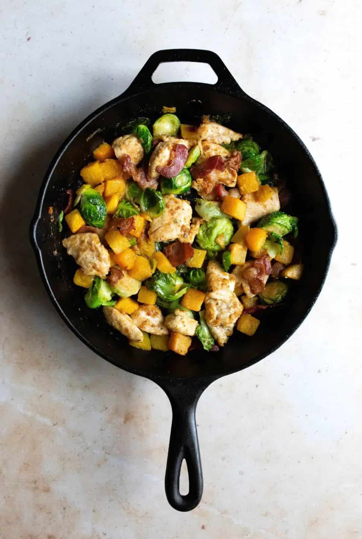 One Pan Chicken and Veggies with Bacon in a black skillet.